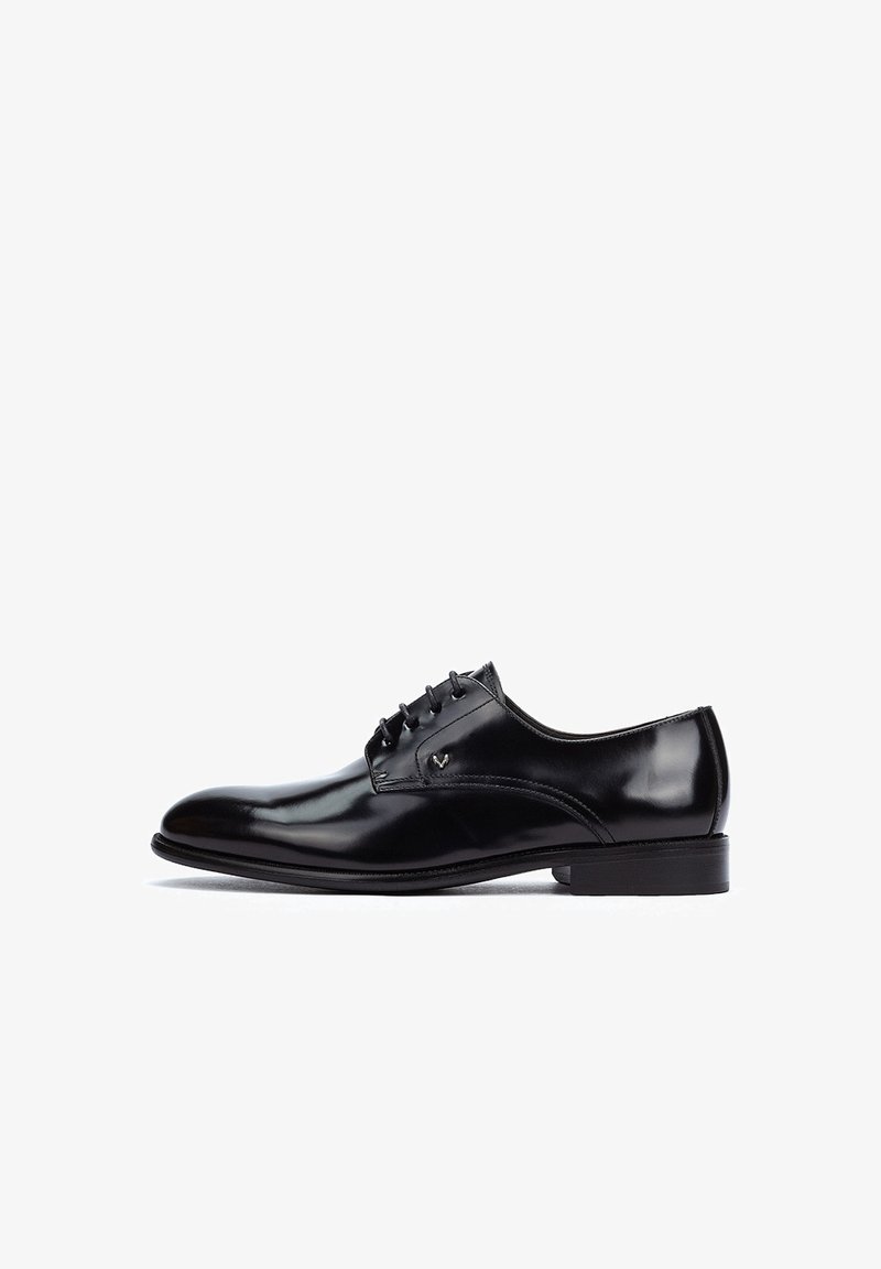 Zapato de vestir de cuero negro con un acabado pulido, forma curva, diseño de cordones y un tacón bajo y plano. Presenta costuras mínimas y un detalle de logo.