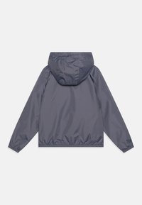 Giacca leggera con cappuccio di colore grigio scuro, realizzata in materiale liscio e resistente all'acqua, con polsini elastici e orlo per una vestibilità sicura.