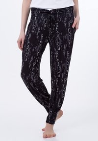 Svarta mönstrade byxor med dragsko i midjan, tapered ben och lätt tyg med vita abstrakta mönster.