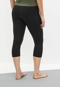 Fekete capri leggings rugalmas anyagból, testhezálló fazonnal, bokáig érő hosszúsággal és lapos varrásokkal a kényelem érdekében.