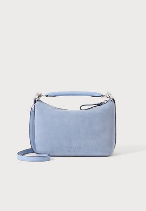 Pequeño bolso de mano de ante azul suave con asa superior y correa de hombro desmontable sobre un fondo blanco liso.