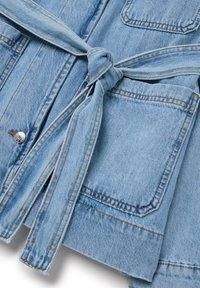 Giacca in denim azzurro chiaro con vita cinturata, due tasche frontali, cuciture in vista e una superficie liscia. Accentuata da un bottone a scatto.