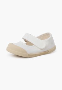 Zapatilla de lona blanca con una puntera y suela de goma beige. Cuenta con una correa de Velcro para asegurarla. Diseño simple sin patrones.