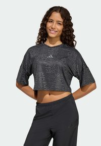 Czarny skrócony t-shirt z fakturowanym nadrukiem w panterkę, okrągłym dekoltem i krótkimi rękawami. Do tego czarne spodnie z elastycznym pasem.