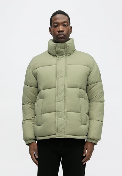 Jasnozielona kurtka puchowa z wysokim kołnierzem, pikowanym wzorem, przednimi kieszeniami i elastycznymi mankietami. Gładki materiał i luźny krój.