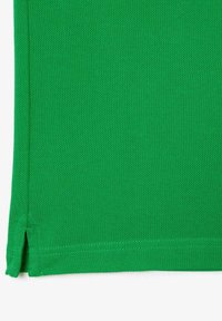 Green fabric textile with a textured surface. The bottom hem features side slits, reinforcing the design detail.
