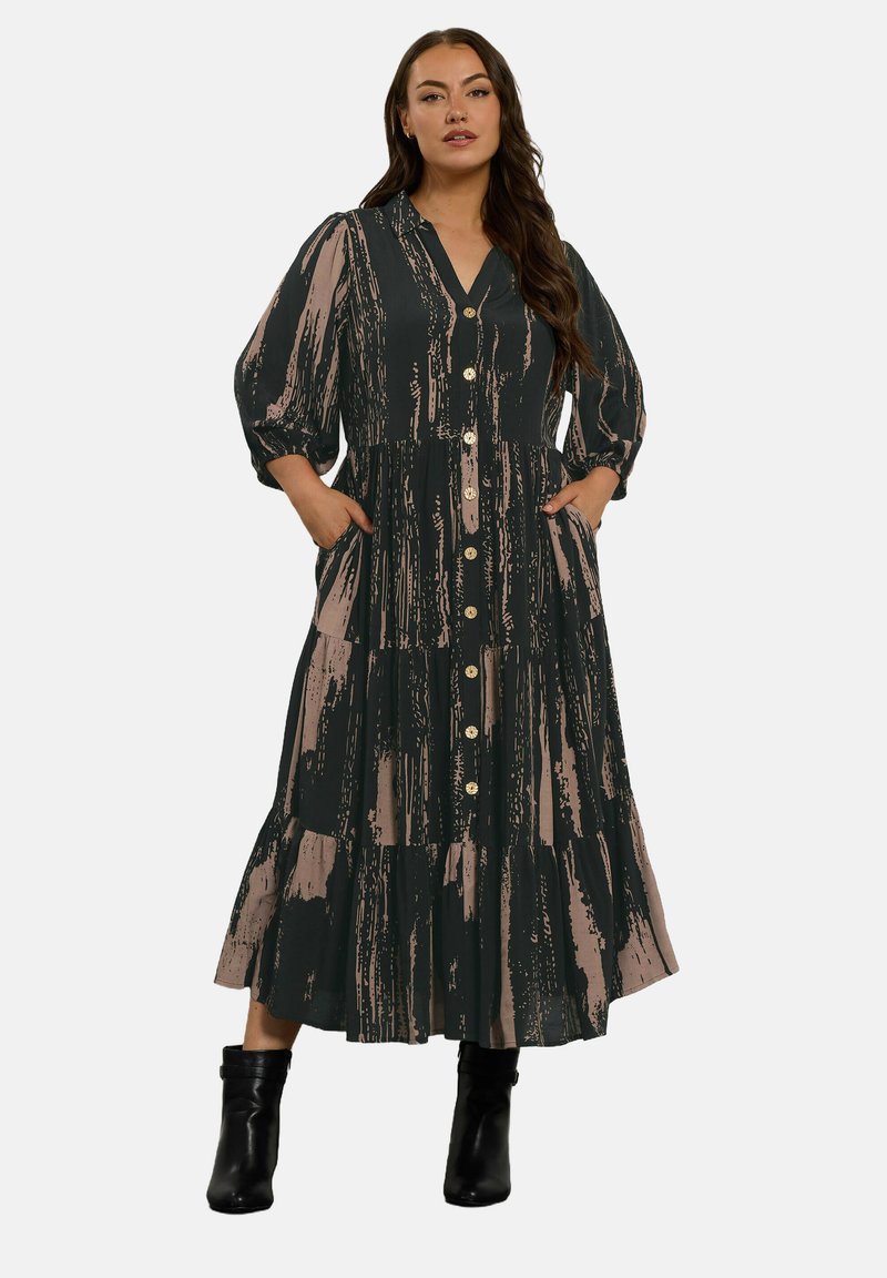Langes, gestuftes Kleid in Dunkelgrün mit beigen Pinselstrichmustern. Verfügt über eine durchgehende Knopfleiste, einen V-Ausschnitt und Puffärmel sowie seitliche Taschen.
