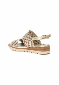 Sandali intrecciati con un design a fasce incrociate in tono marrone e crema. Presentano dettagli metallici dorati, una suola imbottita e una leggera suola in gomma.