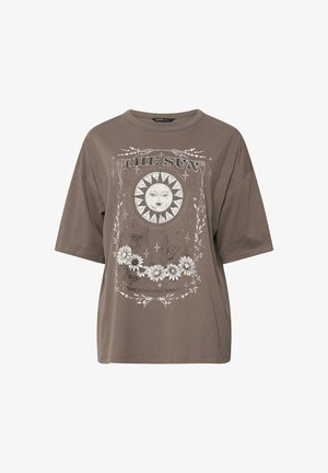 Maglietta marrone oversize con un volto di sole, farfalle, fiori bianchi, stelle e il testo "THE SUN" e "Your existence is magic."
