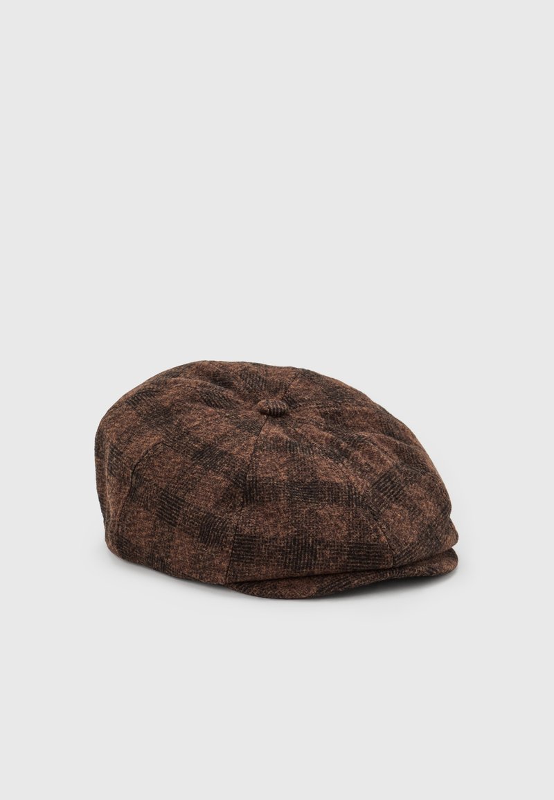 Casquette plate en laine marron avec un motif à carreaux et un petit bouton sur le dessus, présentée sur un fond clair uni.
