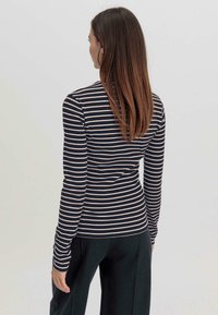 Navy- und cremefarbener gestreifter langärmliger Slim-Fit-Top mit geripptem Textur, featuring einem hohen Kragen und schlankem Design.