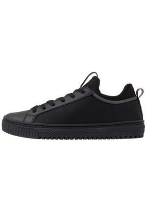 Czarny niski sneaker z teksturowaną gumową podeszwą, sznurowaniem z przodu oraz pętlami na języku i pięcie na białym tle.