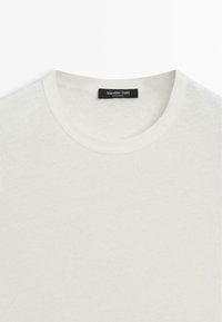 Biała koszulka z okrągłym dekoltem, z czarną metką "Massimo Dutti" wszytą wewnątrz kołnierza, wyprodukowana w Chinach.