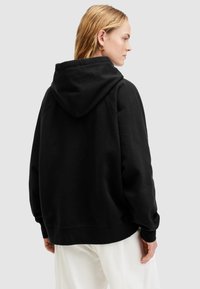 Felpa nera con cappuccio realizzata in tessuto morbido, caratterizzata da una vestibilità rilassata, spalle scese e polsini a coste. Design minimalista senza grafiche.