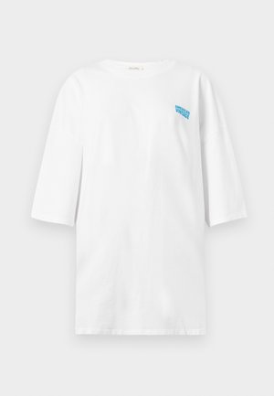 Witte oversized t-shirt met driekwartmouwen en kleine blauwe tekst "American Vintage" op de linkerborst.