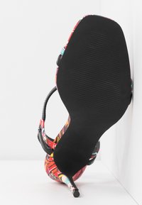 Sandale à talon haut multicolore avec une tige à motifs, des brides noires et une pointe fine. Semelle en caoutchouc noir texturé.