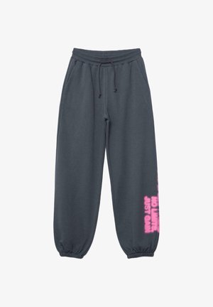Tmavosivé teplákové nohavice s elastickými manžetami, sťahovacou šnúrkou v páse, bočnými vreckami a ružovým nápisom „NO LIMITS JUST GAN“ na dolnej pravej nohe.