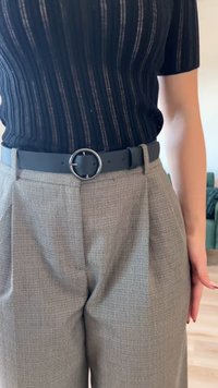 Mustat ribbitopit yhdistettynä vaaleanharmaisiin kuvioituihin housuihin. Leveässä vyötärönauhassa on pyöreä hopea solki mustassa vyössä.