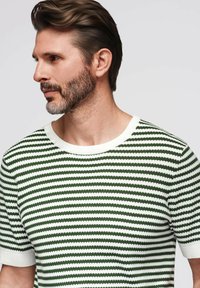 Suéter de punto a rayas verdes y blancas con cuello redondo y mangas cortas. La textura parece suave con un detalle de dobladillo acanalado.