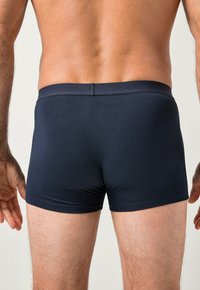 Boxer shorts de color azul marino oscuro, confeccionados con una tela suave y elástica, que presentan una cinturilla de altura media con un logo en relieve en la parte posterior.
