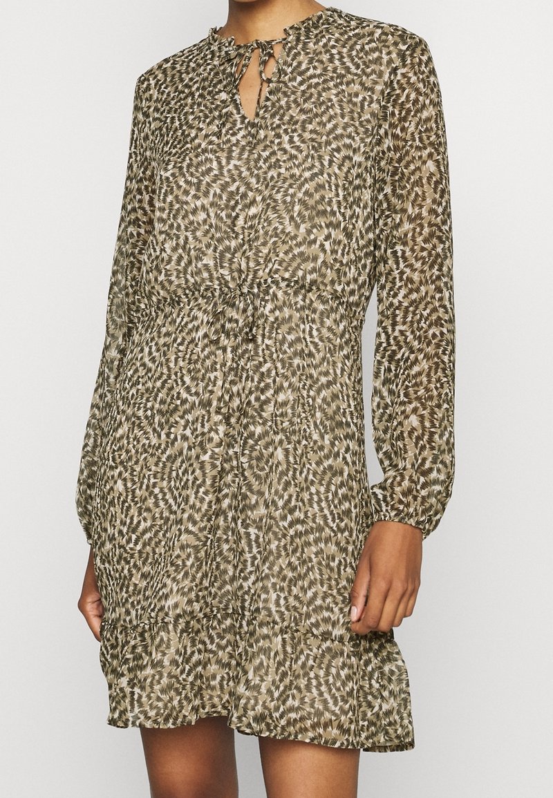 Långärmad klänning i ett brunt och beige abstrakt mönster, med en nyckelhålskant, samlad midja och en volangkant. Lättviktig tyg.