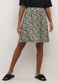 Black floral skirt made of lightweight fabric. Features a loose fit, floral print in cream, and a flared design reaching mid-thigh.