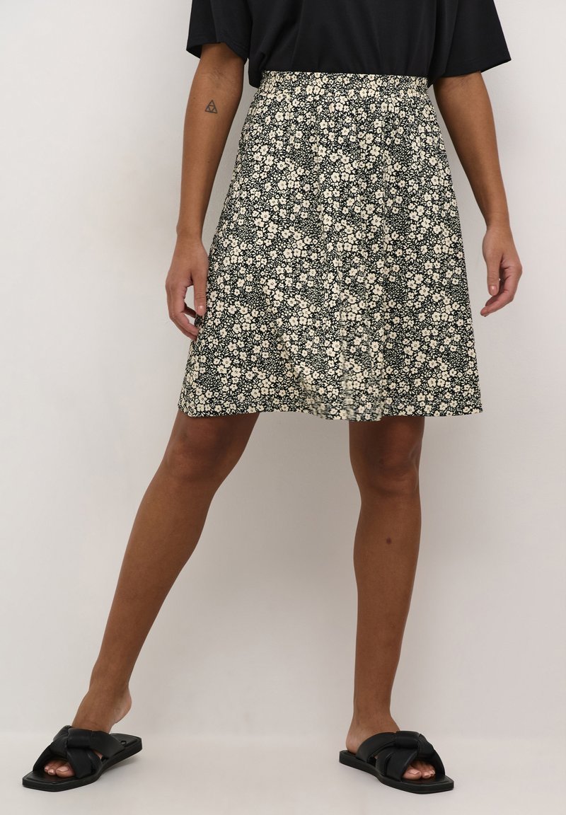 Black floral skirt made of lightweight fabric. Features a loose fit, floral print in cream, and a flared design reaching mid-thigh.
