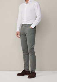 Lichtgewicht witte overhemd met knoop, slim-fit grijze broek en bruine suède schoenen, met voorzakken en een enkele knoopsluiting.