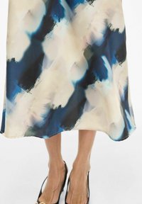 Flytende kjole med abstrakte blå, svarte og beige mønstre. Laget av lett stoff, har en glatt tekstur og er kuttet under kneet.