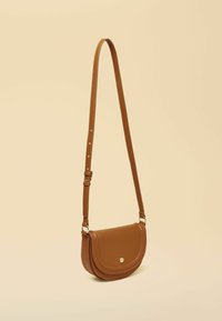 Sac bandoulière en cuir marron avec un rabat arrondi, une fermeture à pression dorée, une sangle réglable et une surface texturée.