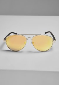 Kuldmetallilised aviator-prillid peegeldava kollase objektiiviga ja mustade plastist templite otstega. Kerge ja minimalistlik disain.