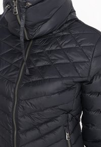 Doudoune noire matelassée avec couture diagonale, fermeture éclair à l'avant, col montant, capuche avec cordons de serrage et poche latérale zippée.