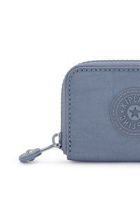 Kipling zippered wallet in textured, light blue fabric with a circular logo and silver hardware. Compact rectangular shape for easy storage.
