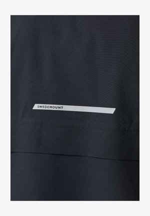 Dunkler Stoff mit einem horizontalen weißen Streifen in der Nähe einer Naht, auf dem der Text "SWEDEMOUNT" steht.