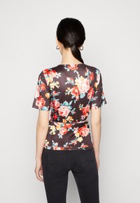 Top floral de mangas curtas com um fundo escuro, apresentando flores vibrantes em vermelho e amarelo, tecido suave e um design ajustado.