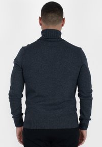 Maglione grigio scuro a collo alto a coste realizzato in tessuto a maglia. Presenta maniche lunghe aderenti e un colletto texture. Design classico.