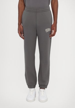 Gray sweatpants with a tapered leg, elastic waistband, and ribbed cuffs. Features a white "Billionaire Boy Club" logo on the left thigh.