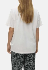 T-shirt en coton blanc avec une coupe décontractée, des manches courtes et un dos uni. Assorti à un pantalon à imprimé léopard gris.