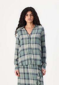 Green plaid button-up shirt with long sleeves, featuring white and navy stripes. Made from a smooth fabric with a relaxed fit.