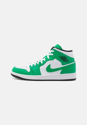 Baskets montantes moyennes avec panneaux en cuir blanc et vert, lacets blancs, détails noirs et logo Air Jordan près de la cheville sur fond blanc.