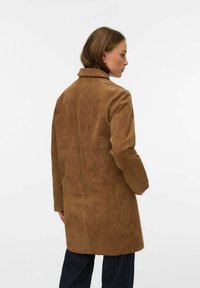 Pruun seemisnahast mantel kraega, pikkade varrukatega ja sirge lõikega. Sile pind ja seljal nähtavad õmblused.