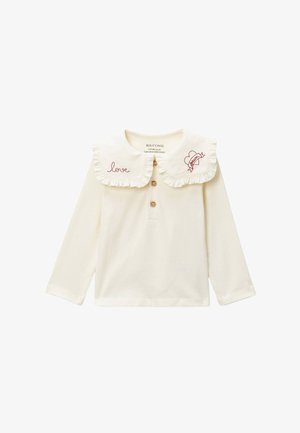 Haut crème à manches longues avec grand col à volants, patte de boutonnage, broderie "love" et cœur avec "dream" sur les bords du col.