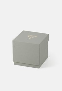 Quadratische Geschenkbox aus strukturiertem, hellgrauem Material. Verfügt über ein dreieckiges, goldenes Logo auf dem Deckel. Mit einem Klappenverschluss geschlossen.