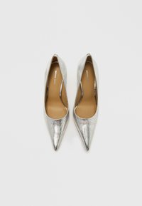 Sølvmetallic høje hæle med spidst tådesign, glat tekstur og en mærkeindlægssål synlig mod en neutral baggrund.