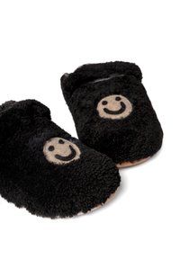 Czarne pluszowe kapcie o miękkiej, puszystej fakturze, z beżowym wzorem uśmiechniętej buźki z przodu i brązową podeszwą.