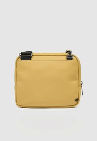 Borsa rettangolare gialla in materiale liscio. Presenta una cerniera superiore e una tasca laterale, con dettagli neri e cinghie regolabili.