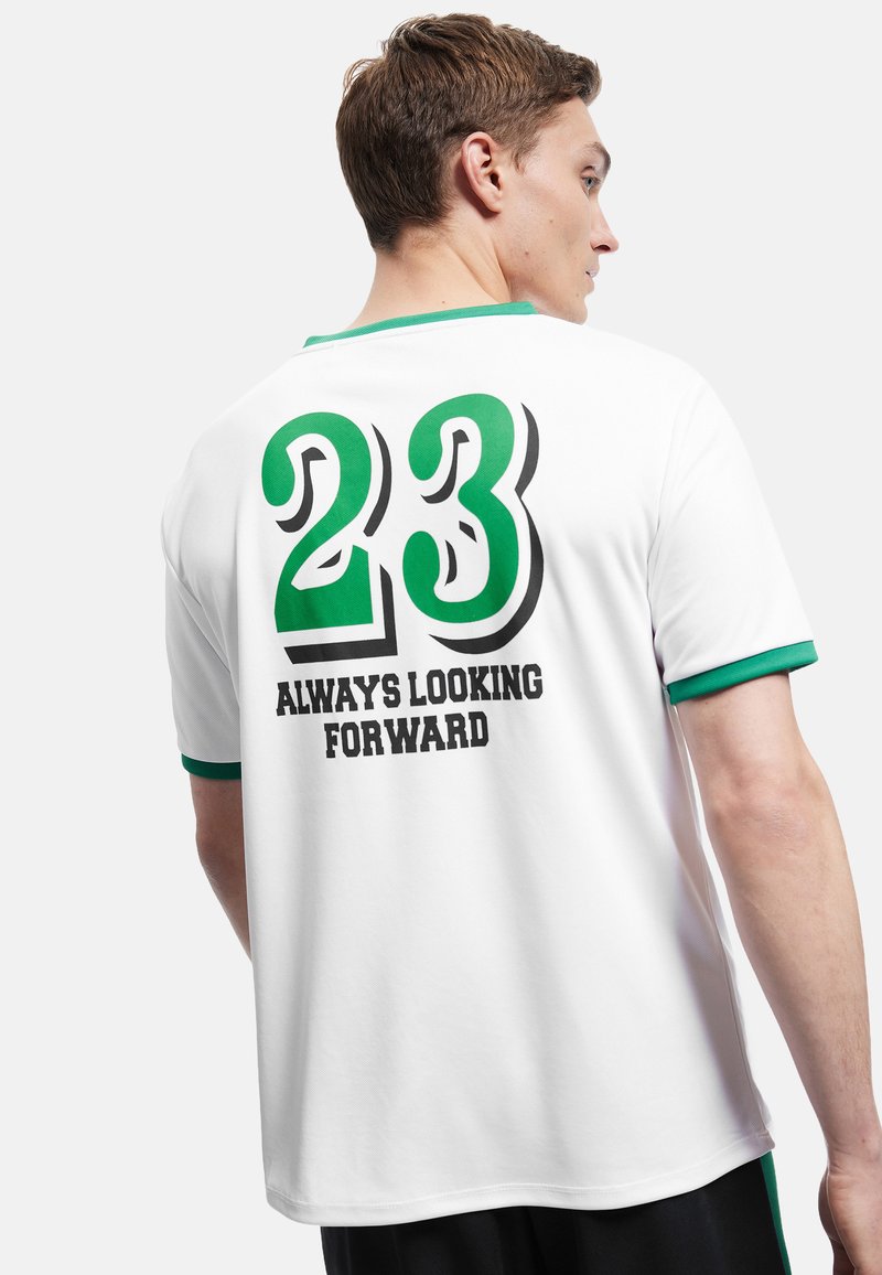 Biała koszulka sportowa z zielonym kołnierzykiem i akcentami. Z tyłu duża liczba "23" w kolorze zielonym i czarnym oraz napis "ZAWSZE PATRZYMY DO PRZODU."
