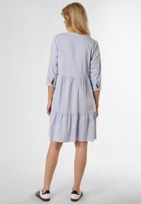 Lichtblauw gestreepte jurk met driekwart mouwen, gelaagde rok, ronde halslijn en uitsparingen op de manchetten.