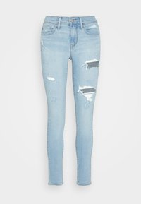 Vaqueros skinny de color azul claro, fabricados en denim, con zonas desgastadas y rasgados visibles, un clásico diseño de cinco bolsillos y dobladillos deshilachados.