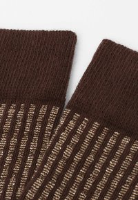 Calze marroni in maglia con design a coste, caratterizzate da strisce alternate di marrone chiaro e filamenti metallici lungo il corpo.